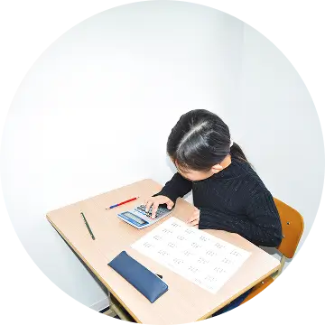 机に向かい、電卓とプリントで学習している様子