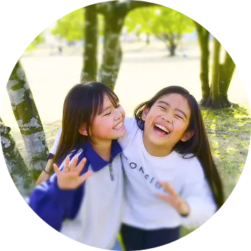 2人の子共が公園で笑い合い、仲良く手を振っている様子